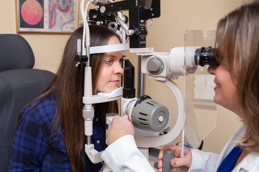 An optometrist examining a patient's eyes at a slit lamp
