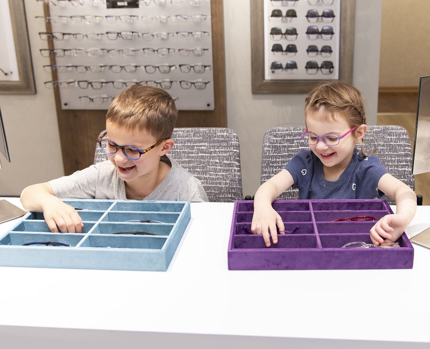 Two children trying on frames in the optical shop